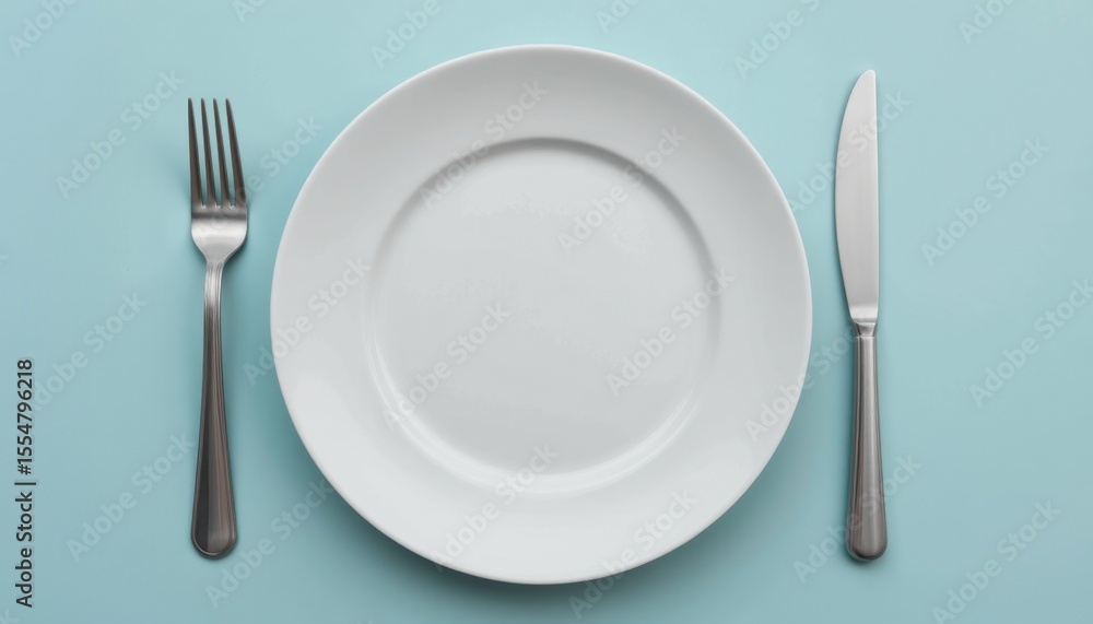 Setting the table for a gourmet meal elegant plate and cutlery arrangement on a soft blue surface Setting the table for a gourmet meal elegant plate and cutlery arrangement on a soft blue surface