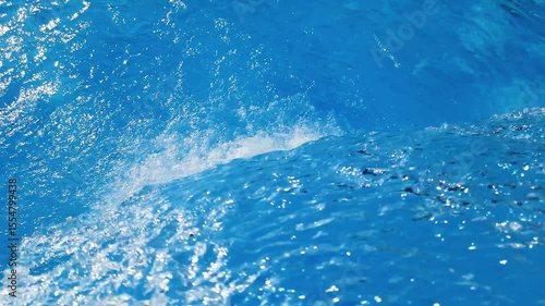 Video footage of blue clear water falling into a blue pool.