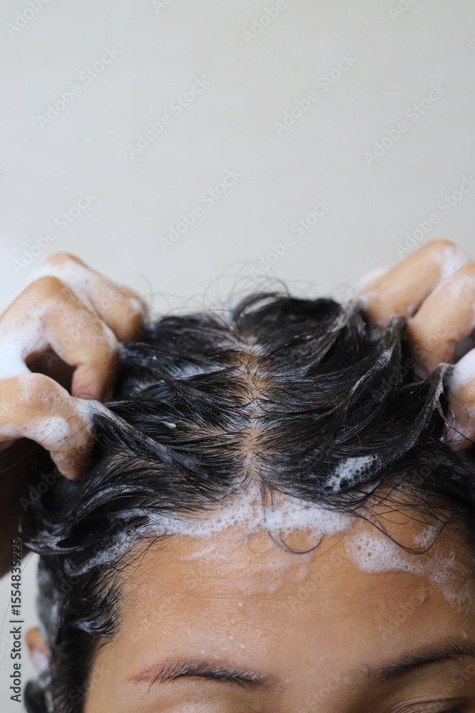 Naklejka premium A woman is taking a shower and washing her hair in the bathroom.