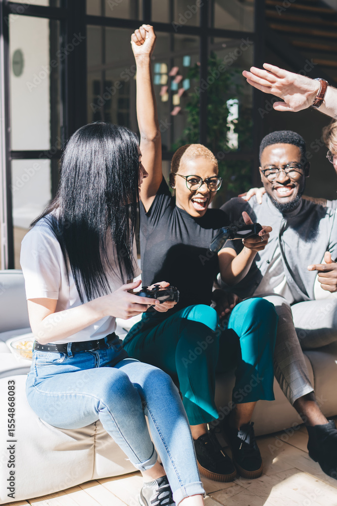 © BullRun - Diverse cheerful company of friends celebrating victory after playing video games