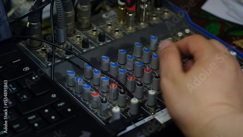 a man's hand turns a sound console