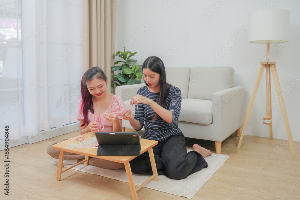 Two young asian women stringing beads on thread and choosing colorful beads from box to making handmade bracelet while spending time to creating jewelry handicraft and doing hobby lifestyle at home. Two young asian women stringing beads on thread and choosing colorful beads from box to making handmade bracelet while spending time to creating jewelry handicraft and doing hobby lifestyle at home.