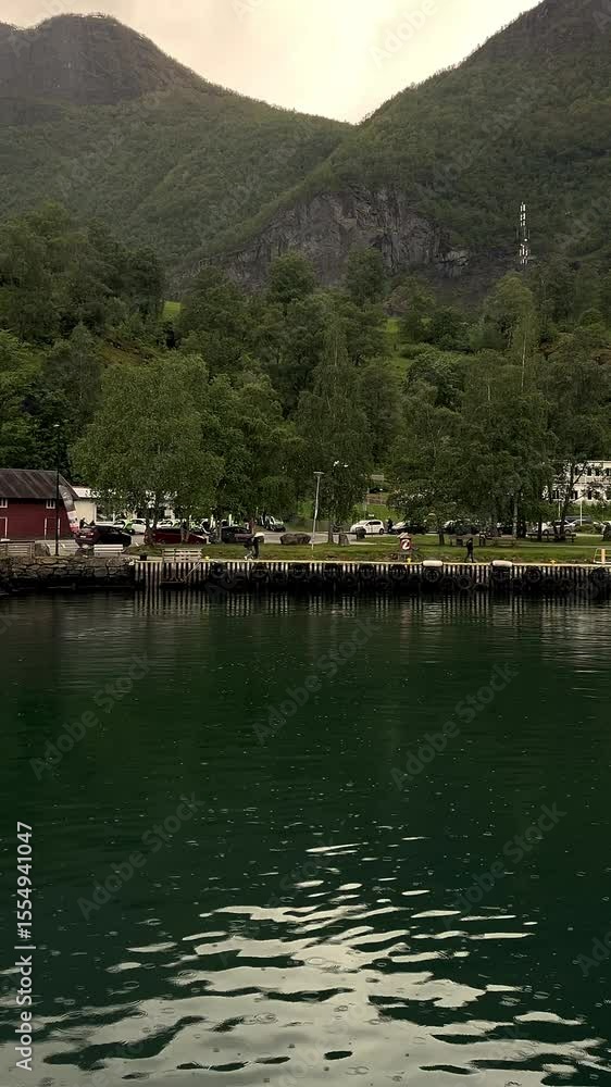 Small pier with yachts and mountains in background. Calm water, clear sky, picturesque Nordic landscape. Suitable for travel, Norway, fjords or nature themes. Small pier with yachts and mountains in background. Calm water, clear sky, picturesque Nordic landscape. Suitable for travel, Norway, fjords or nature themes.