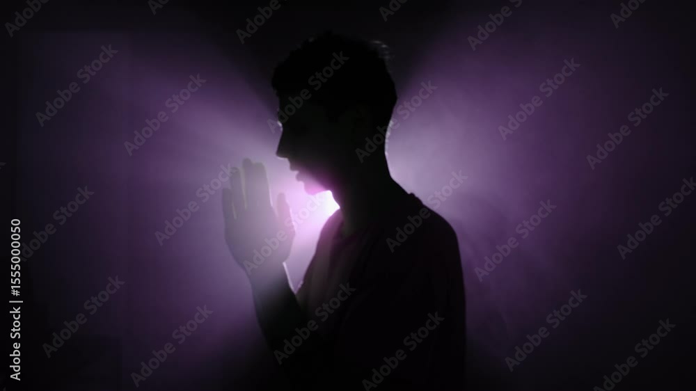 Silhouette of man praying in purple mist with divine light shining behind, symbolizing inner search and spiritual awakening. Silhouette of man praying in purple mist with divine light shining behind, symbolizing inner search and spiritual awakening.