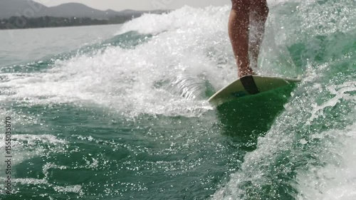 Athletic man wake surfing on lake