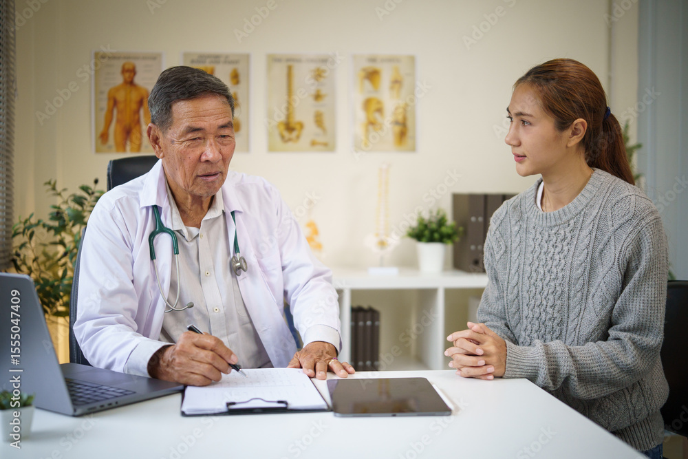 Obraz premium Senior male doctor explaining medical information to a young female patient during consultation.
