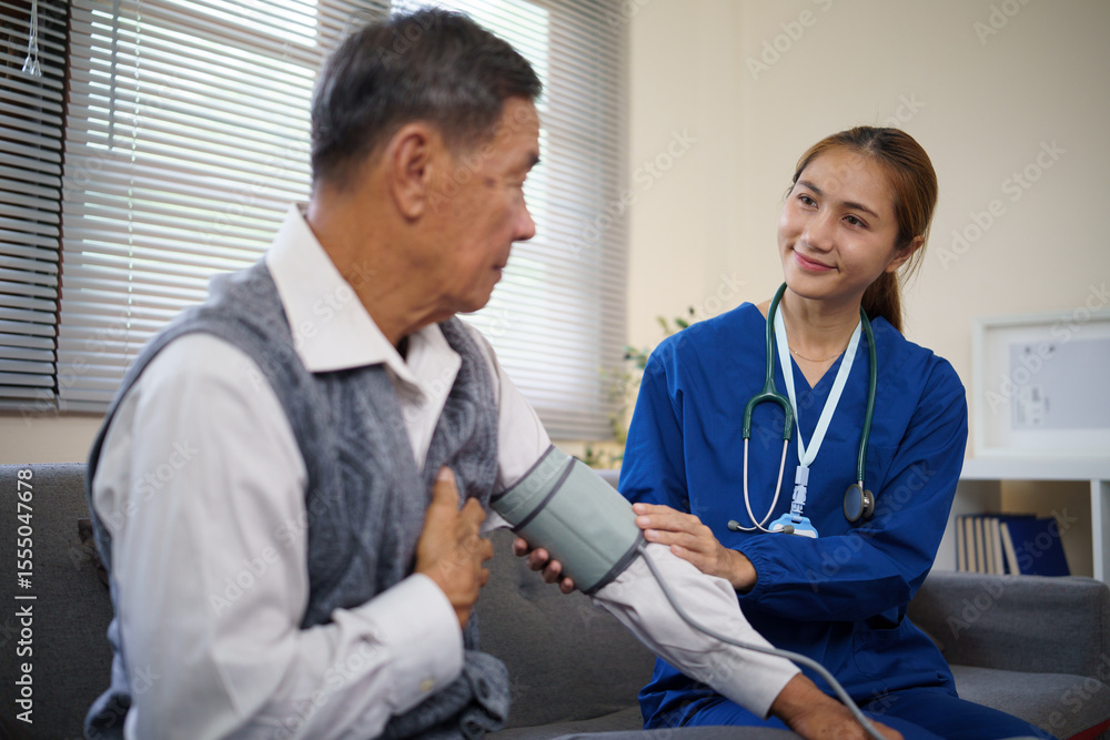 Obraz premium Female nurse measuring blood pressure of an elderly man during a home healthcare visit.