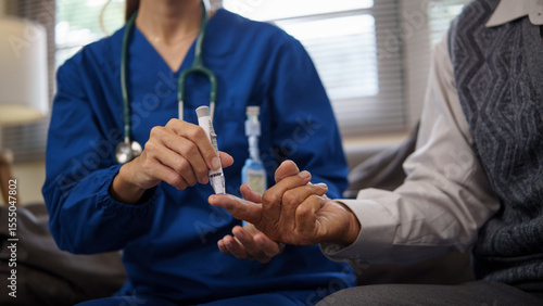 Home caregiver  using lancet to check blood sugar levels of older patient.  Health care concept.