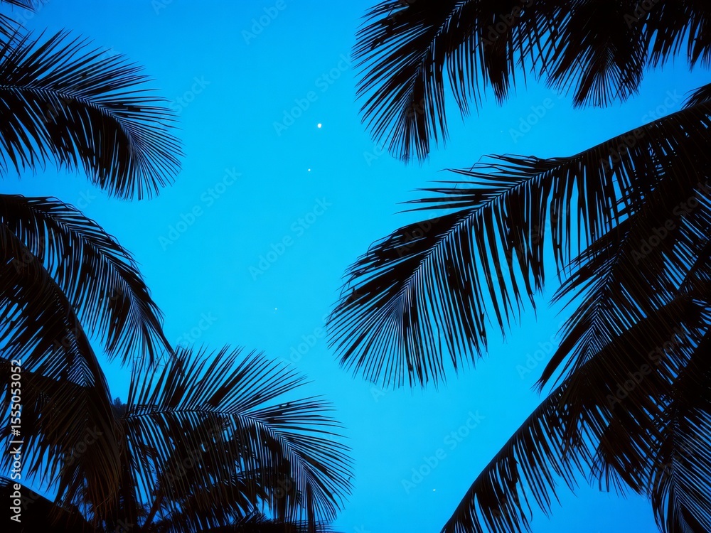 Fototapeta premium Silhouette of palm tree fronds against a bright blue sky creating a tropical paradise viewscape