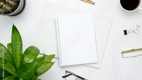 Blank notebook mockup. White workspace with cactus, green plant, eyeglasses, coffee mug for productivity