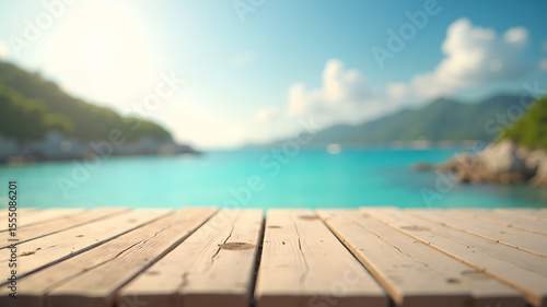 Warm sunlight highlights textured wooden planks in sharp focus, blending into a dreamy blurred background of blue waves, rocky coastlines, lush hills, and a bright sky with fluffy white clouds.