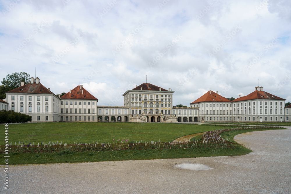 Naklejka premium Historic palace surrounded by serene gardens and cloudy skies in a tranquil setting in Munich, Germany