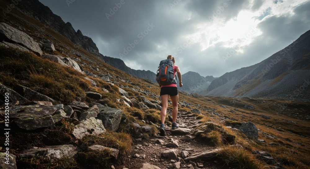 Fototapeta premium Trailblazer Woman Hiking High Peaks with Cloudy Sky Adventure.
