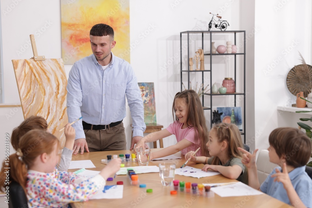 Fototapeta premium Man teaching kids to draw at painting lesson indoors