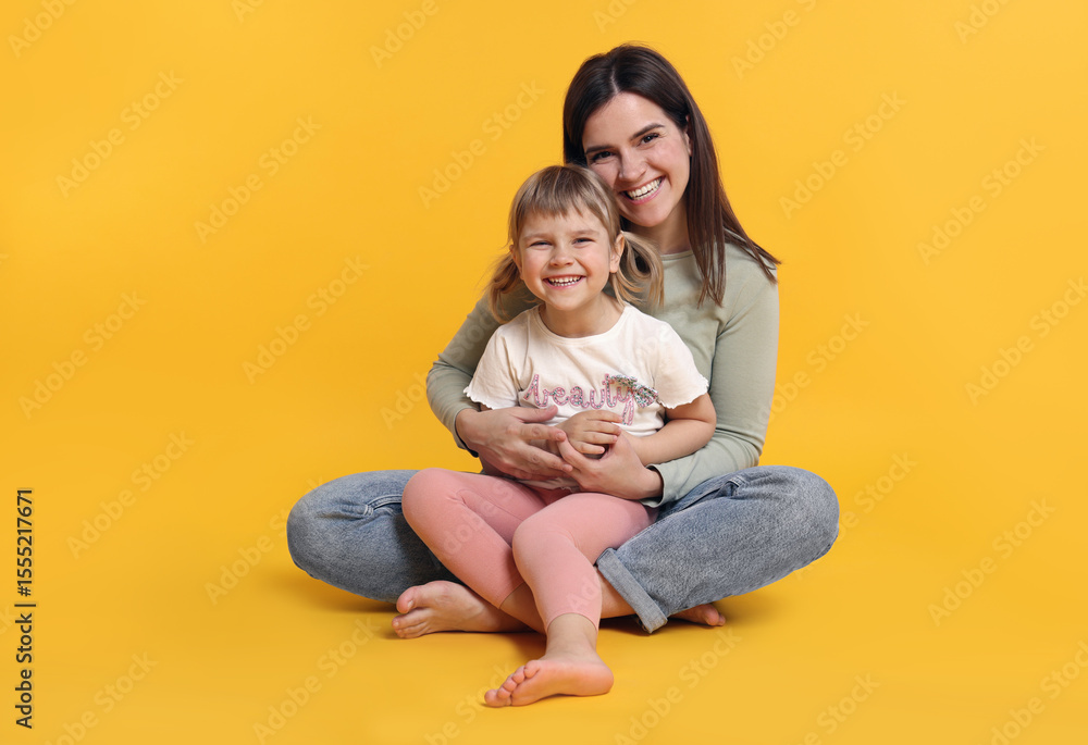 Happy mother and her cute daughter on orange background Happy mother and her cute daughter on orange background