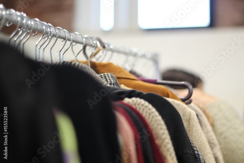 cabideiro com roupas de segunda mao em feira de consumo consciente, feira de economia circular, fundo desfocado e luminoso.