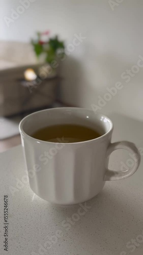 Slow dolly out from tea cup on cozy wooden table in warm light