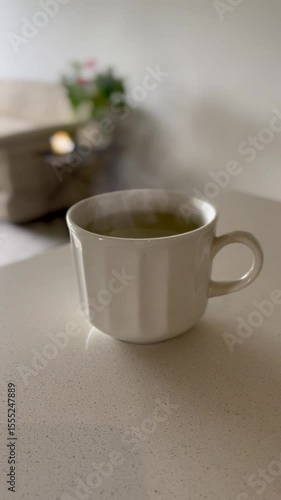Cozy tea scene with cup in focus and blurred warm living room background