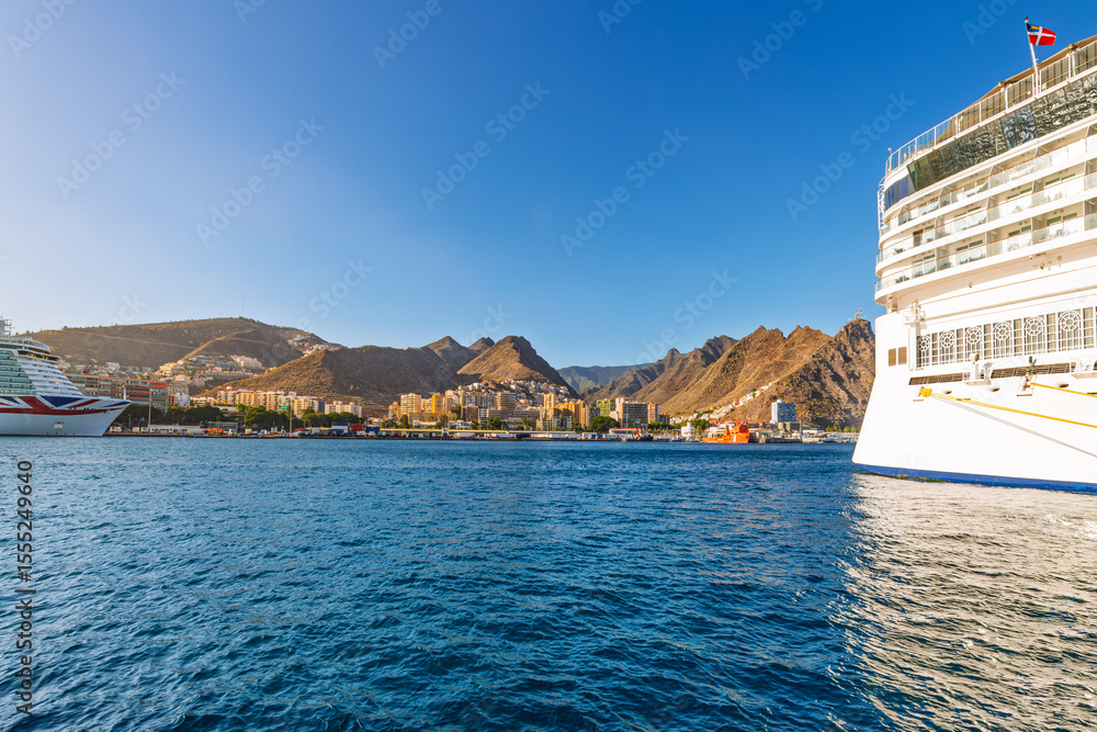 Naklejka premium Large cruise ships dock at the Port of Santa Cruz de Tenerife, Spain, on the Canary Island of Tenerife, with the seaside skyline and volcanic mountains in view.