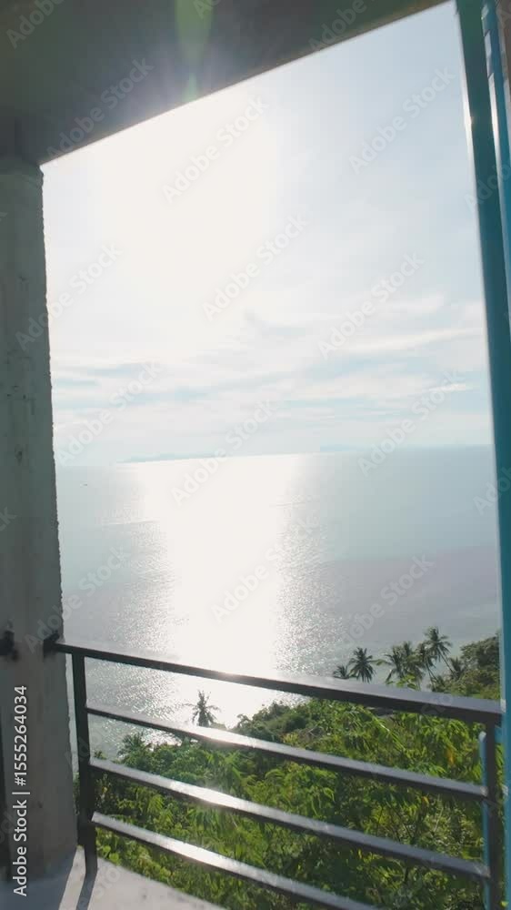 Vertical video. Man Sitting on Terrace Looking at Phone While Drone Flies Past Showing Coastal View from Hillside Vertical video. Man Sitting on Terrace Looking at Phone While Drone Flies Past Showing Coastal View from Hillside