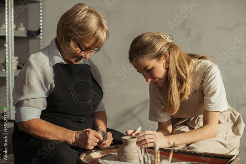 Photography Experienced and young craftswomen creating pottery together in workshop