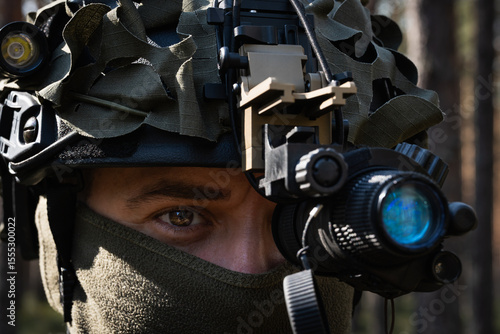 Obraz na plátně Close-up of a special forces soldier in a tactical helmet with a night vision device during an operation in the forest