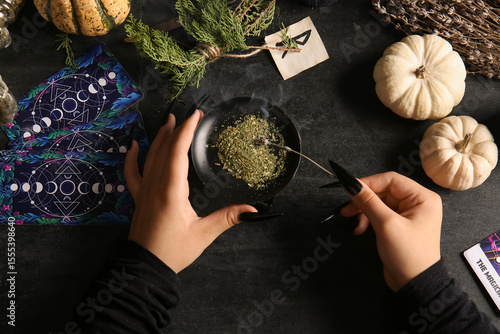 Witch burning herbs on dark...