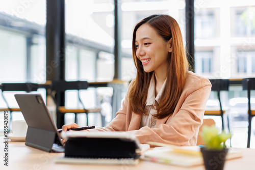 Fotografie Young busy professional asian business woman company executive or entrepreneur using digital tablet working sitting at desk in office looking at tab, managing financial project data