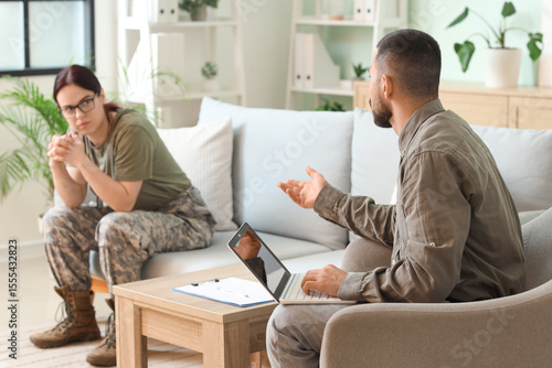 Male psychologist talking to female soldier with PTSD in office, back view