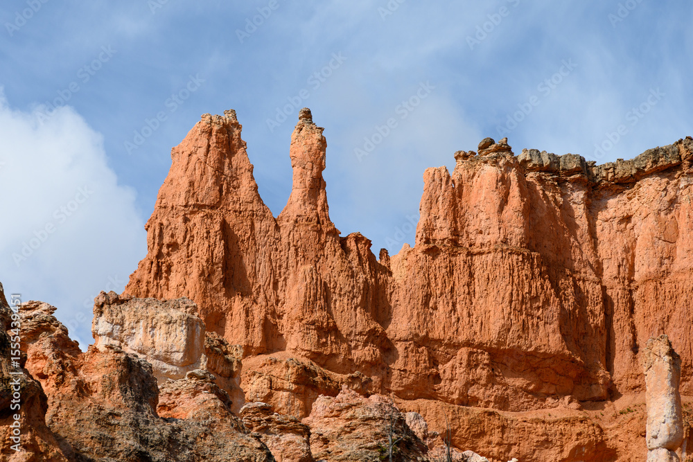 Fototapeta premium Looking up from base of the amphitheater on queens trail at dramatic orange rock hoodoos, summer vacation exploring in Bryce Canyon National Park, Utah 