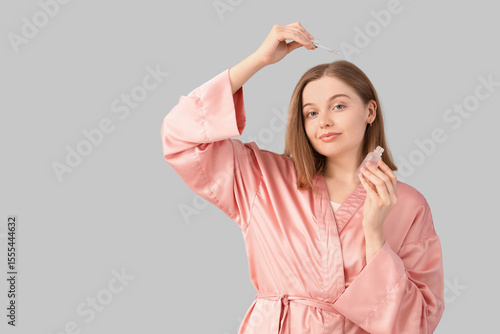 Young woman using serum for...