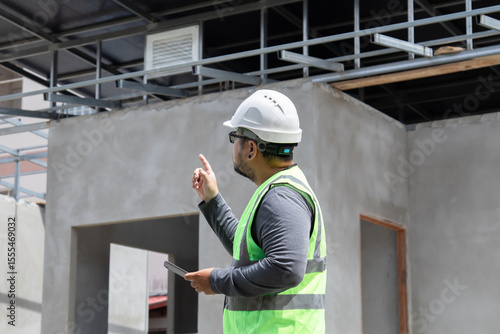 Bilde på lerret Asian construction project foreman with beard inspects construction site using t