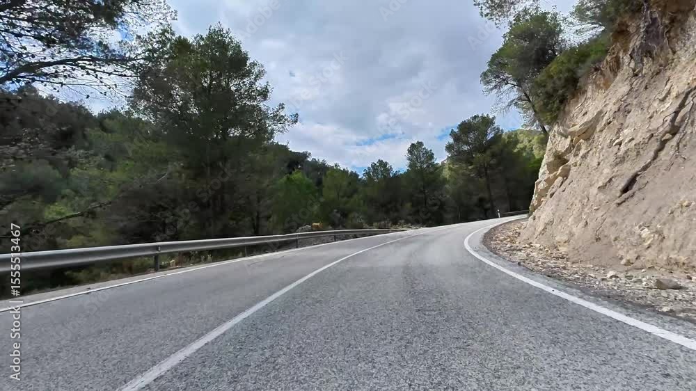 A breathtaking scenic view of a winding curvy mountain road, beautifully framed by lush trees and rocky terrain A breathtaking scenic view of a winding curvy mountain road, beautifully framed by lush trees and rocky terrain
