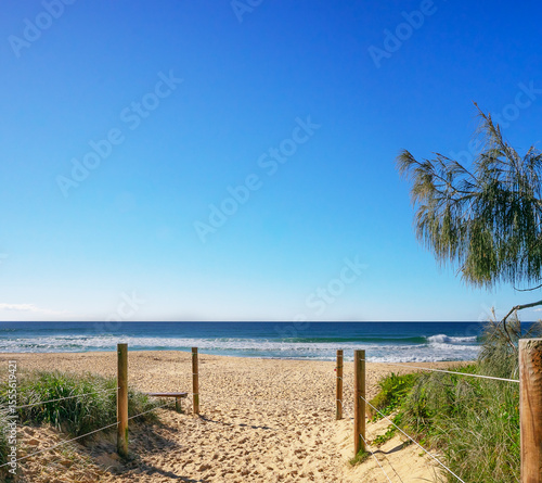 A beach lifestyle backgound with a sandy beach access walkway, horizon,surf waves, sand and blue sky elements and copy space
