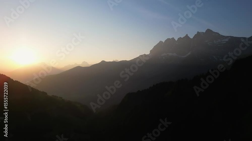 Beautiful Drone sunset in the Swiss Alps. The drone flys down below the mountain line as the sun sinks below the horizon and beautiful sun rays shine down across the valley. 