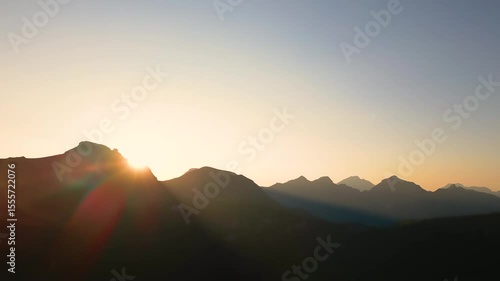Beautiful Drone sunset in the Swiss Alps. The drone flys down below the mountain line as the sun sinks below the horizon and beautiful sun rays shine down across the valley. 
