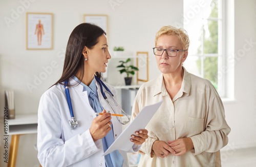 Photos Professional doctor in white coat discussing results of medical tests with older female patient in bright office