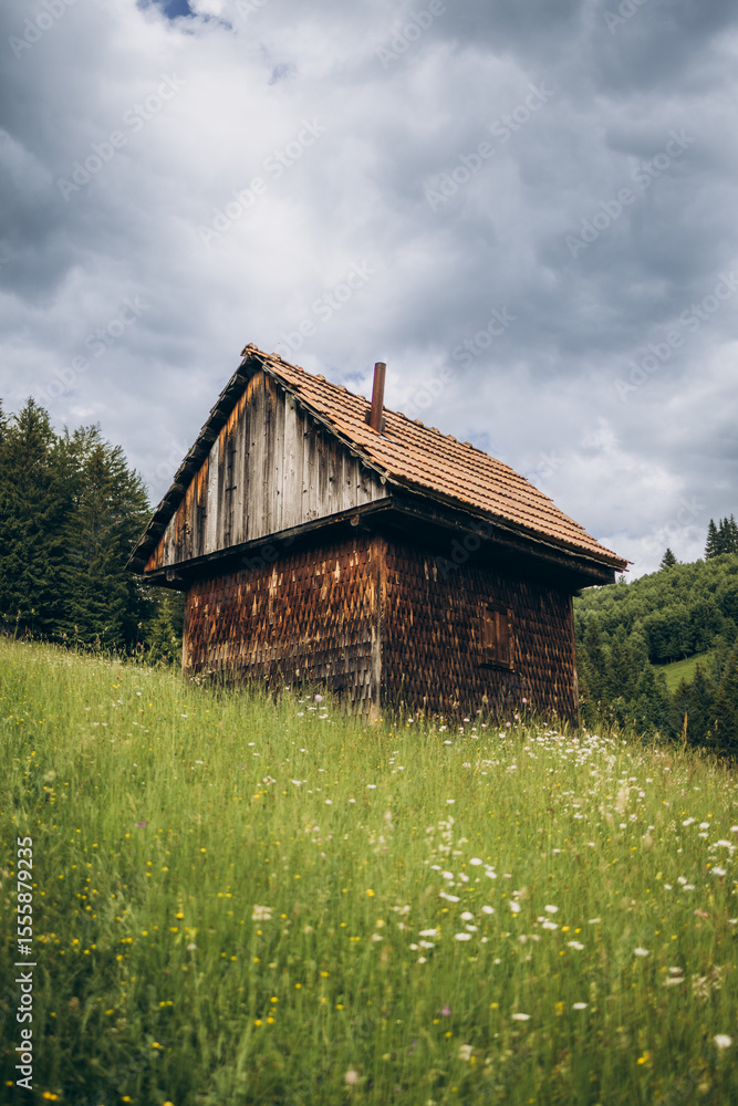 Wooden cabins nestled on a mountain slope overlook vast green meadows, creating a cozy and peaceful countryside retreat. Wooden cabins nestled on a mountain slope overlook vast green meadows, creating a cozy and peaceful countryside retreat.