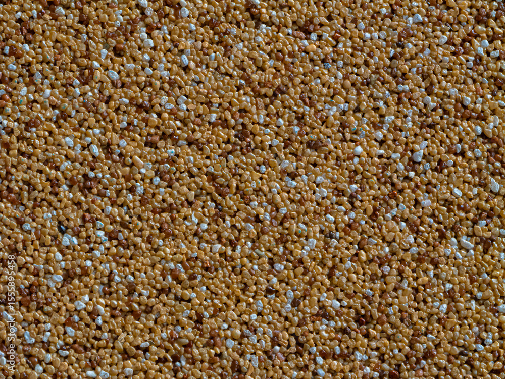 Fototapeta premium Close-up of decorative resin-bound gravel render used in exterior architecture. Textured wall surface made of colored pebbles set in synthetic resin