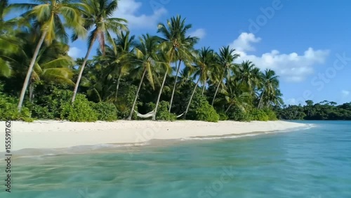 Tropical paradise beach with palm trees and hammock under blue sky