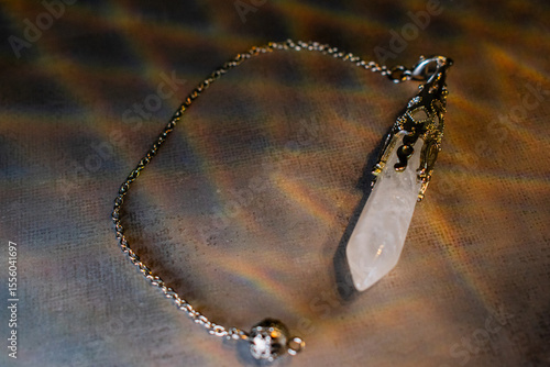 An ornate crystal quartz pendulum with a silver chain, ideal for divination, spiritual healing, and mindful practices. Perfect for esoteric, wellness, and mystical themes.