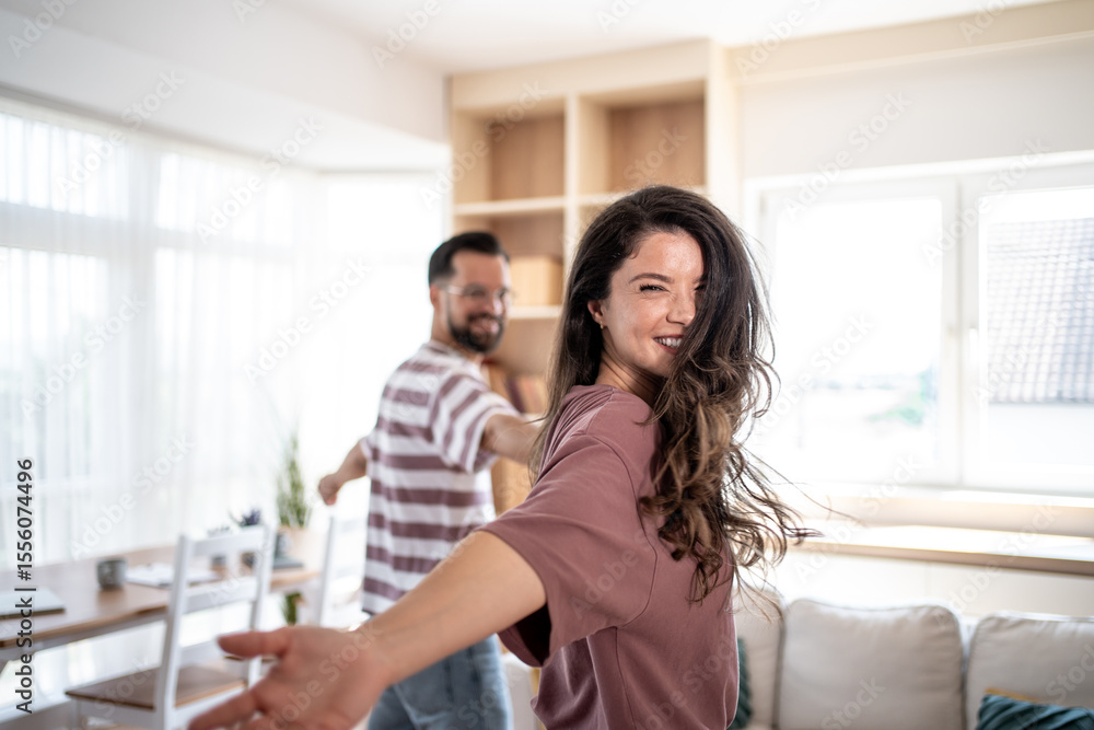 Happy couple holding hands and spinning around in living room Happy couple holding hands and spinning around in living room