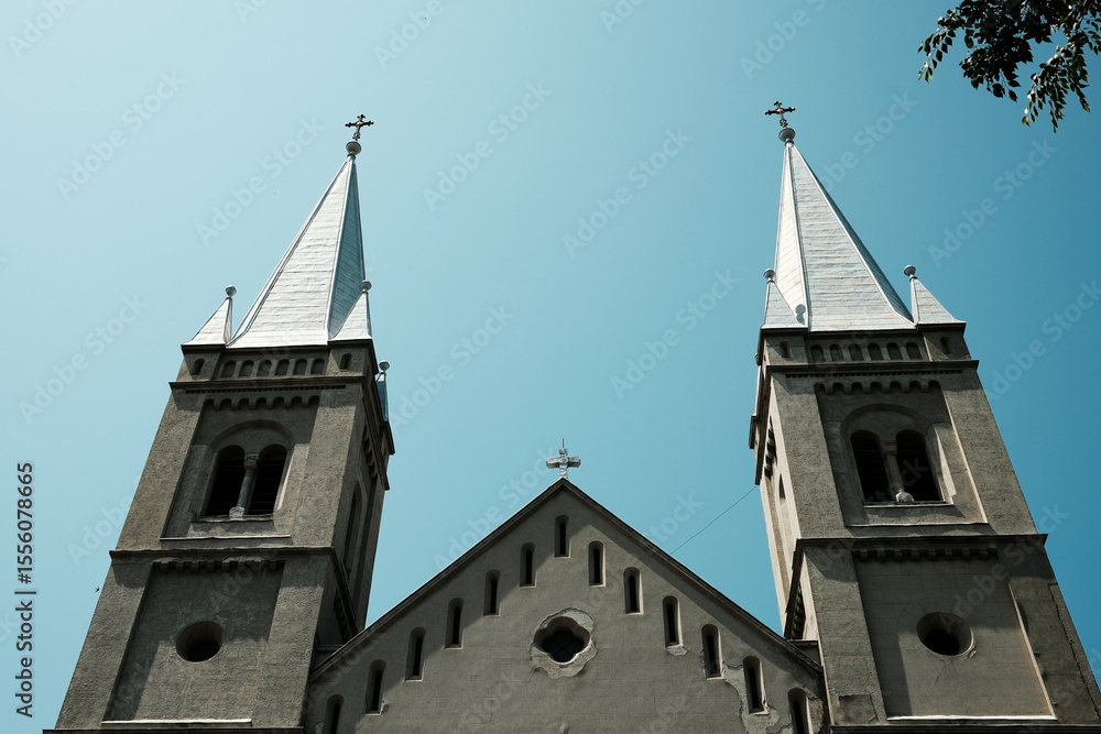 Obraz premium A dramatic close-up of the symmetrical twin spires of the Subotica church, captured against a deep blue sky from a low angle. Serbia country.