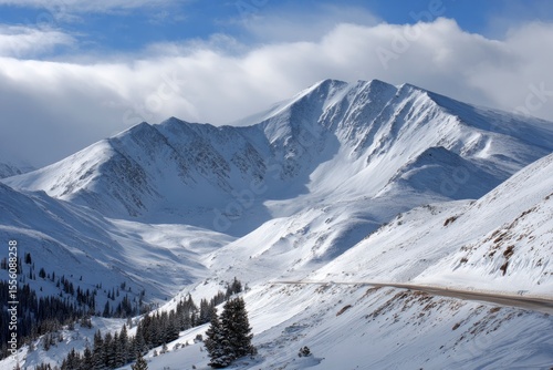 Wallpaper Mural Snowcovered mountain landscape with a winding road and evergreen trees under a partly cloudy sky Torontodigital.ca
