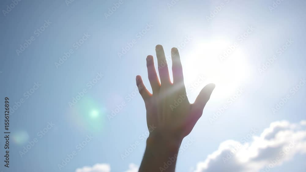Hand reaching toward bright sun in blue sky with clouds Hand reaching toward bright sun in blue sky with clouds