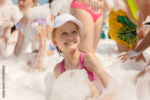 Cute little girl having fun at foam party.