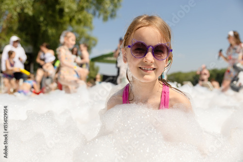 Cute little girl having fun at foam party.