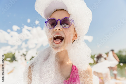 Cute little girl having fun at foam party, close-up, copy space.