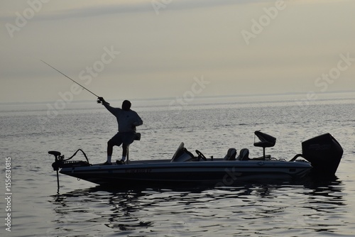 Angler fishing at sunrise in a boat