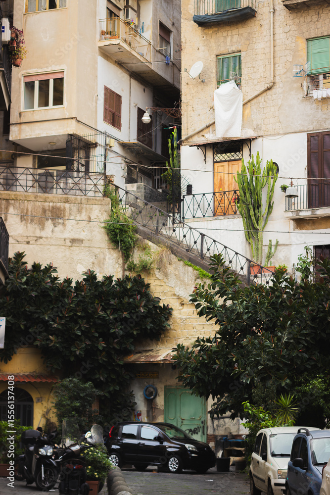 Fototapeta premium A charming street in Naples, Italy showing Mediterranean architecture, potted plants, laundry, and a sense of lived-in authenticity and local life. 